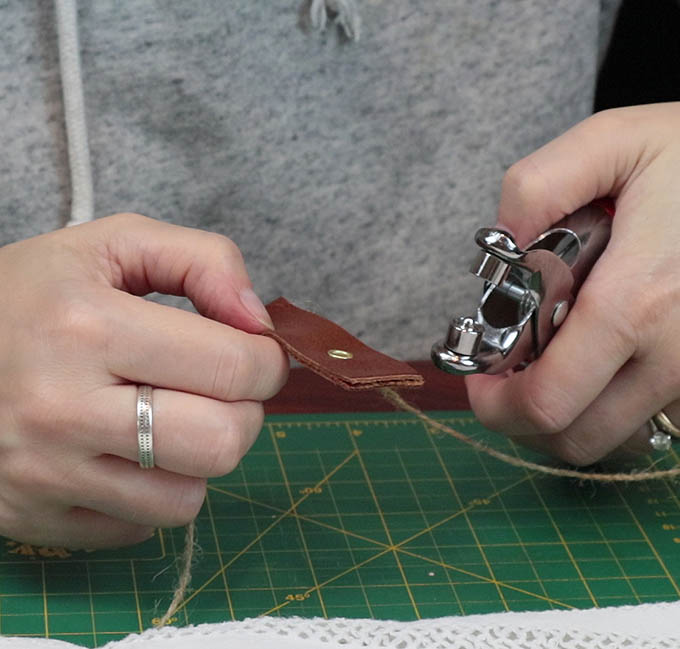 Setting the eyelets in the leather tab in order to hang my DIY wall hanging - this step is optional in this project!