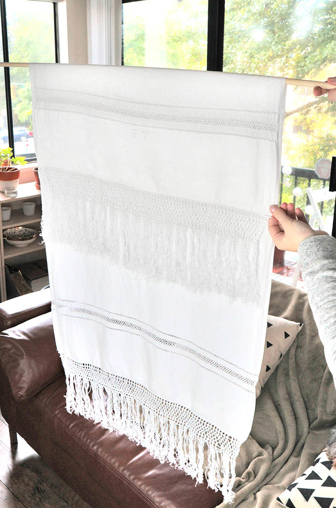 Showing how to fold the fabric over the wooden dowel for this easy DIY wall hanging project
