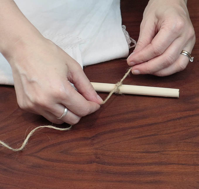 Tie the jute string in a know on both sides of the wooden dowel rod