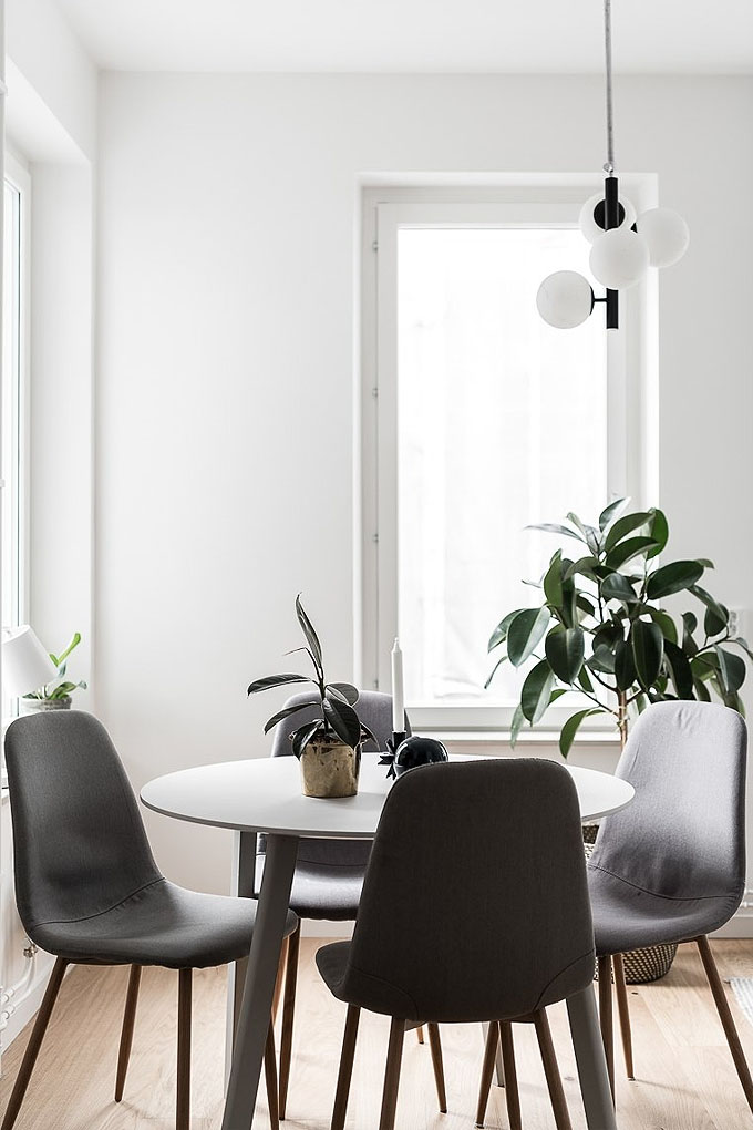 Wonderful example of scandinavian interior design and decor: a bright dining room with botanicals, modern airy furniture and a simple light fixture.