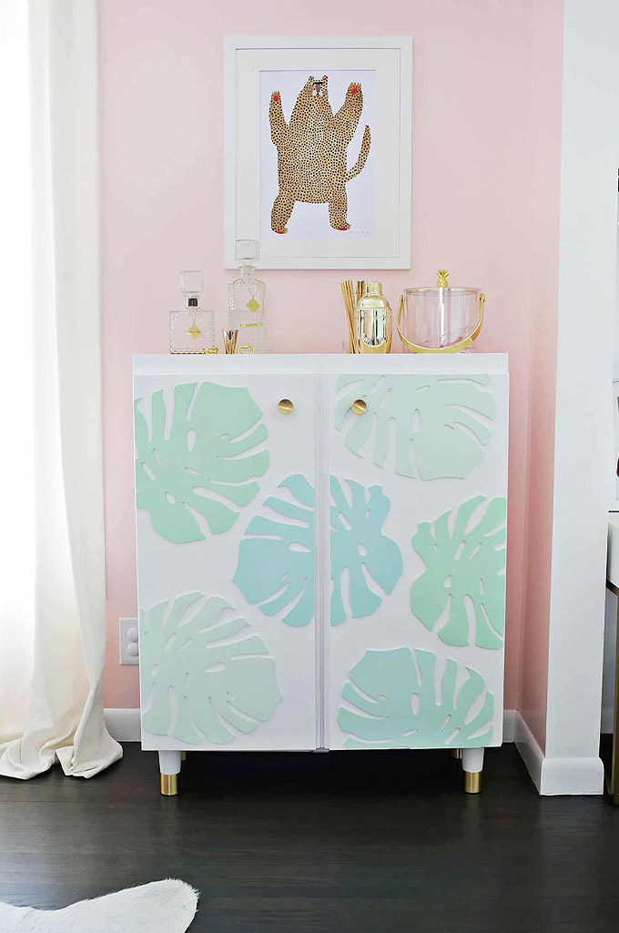 wooden monstera cut outs were applied to this ikea ivar cabinet as a beautiful hack to create a bar cart!