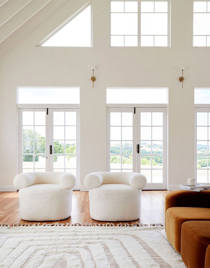 two white accent chairs in a bright airy room with large windows