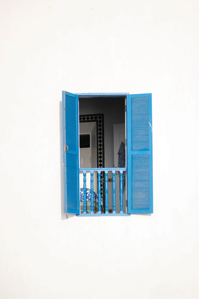 an open bright blue window on a simple white home 