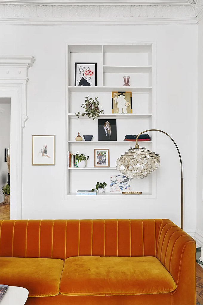 white living room with bright orange velvet sofa