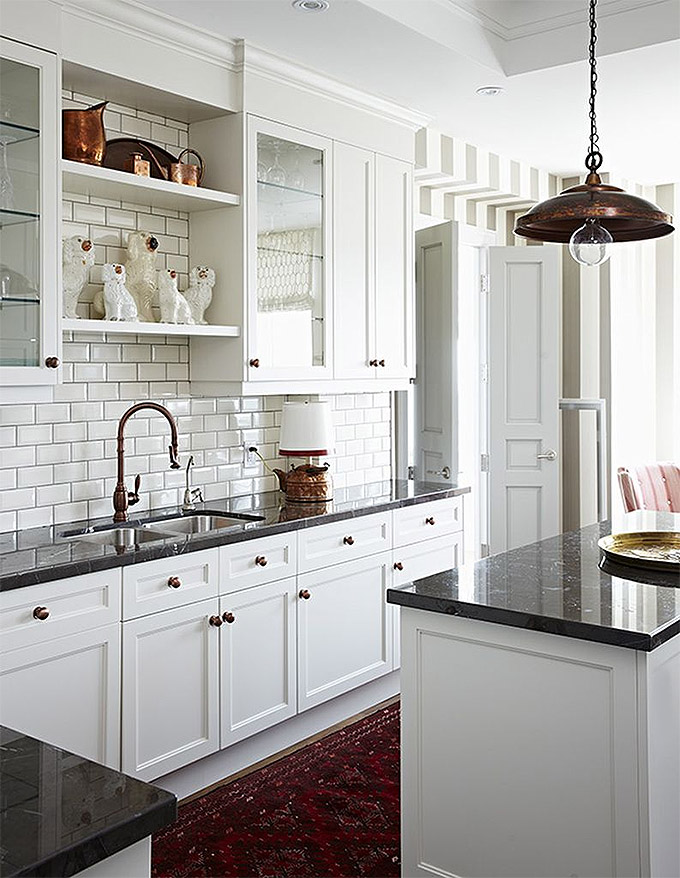 traditional white kitchen with black countertops, white cabinets and vintage rug