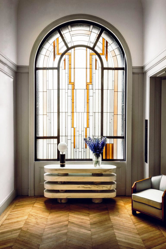 large stained glass window is the backdrop to a marble art deco inspired console