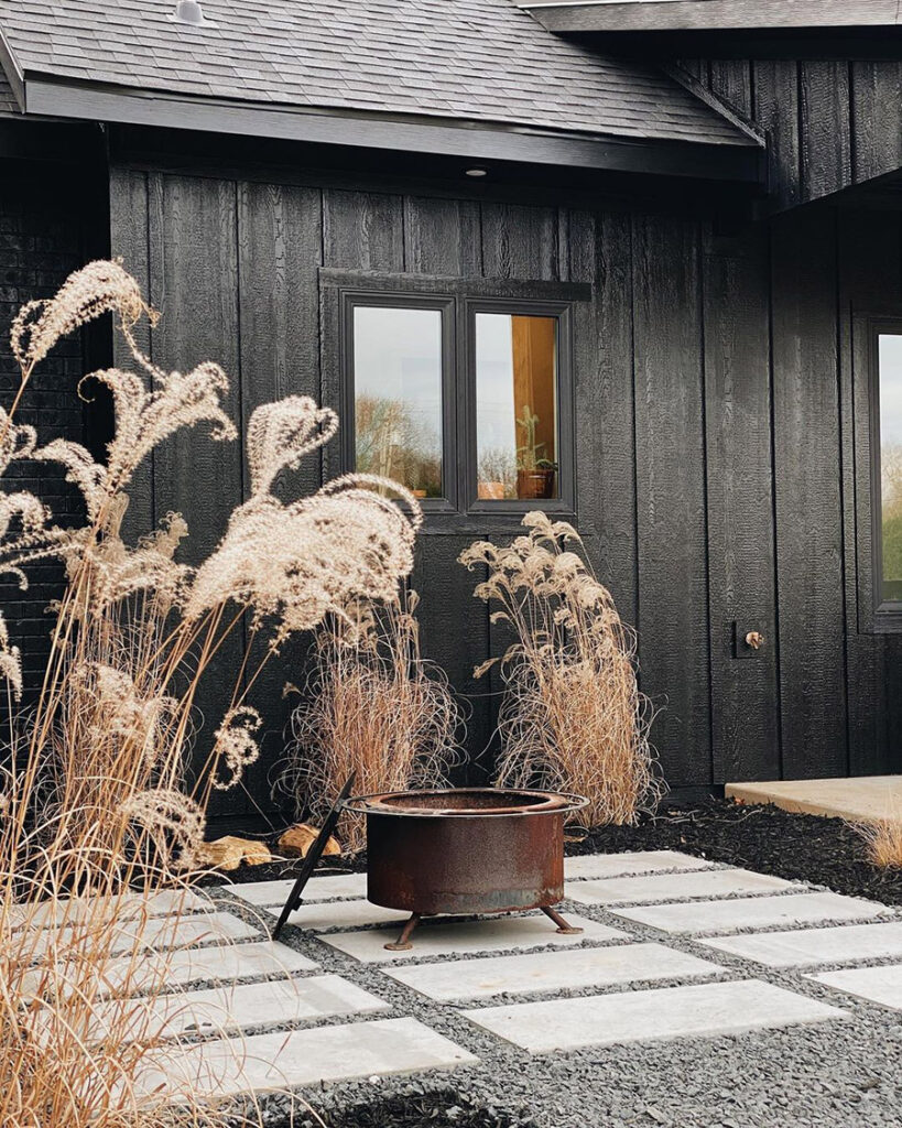 home with black exterior and dried foliage