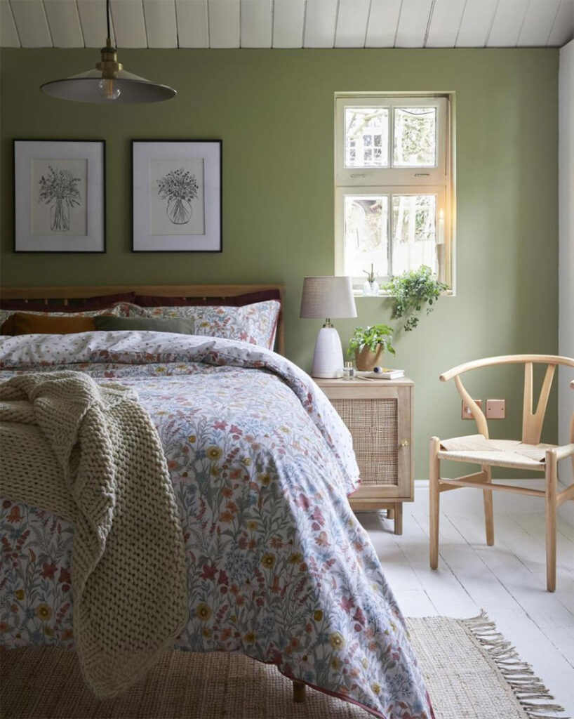 sage green bedroom with light natural wood and rattan accents and shiplap ceiling