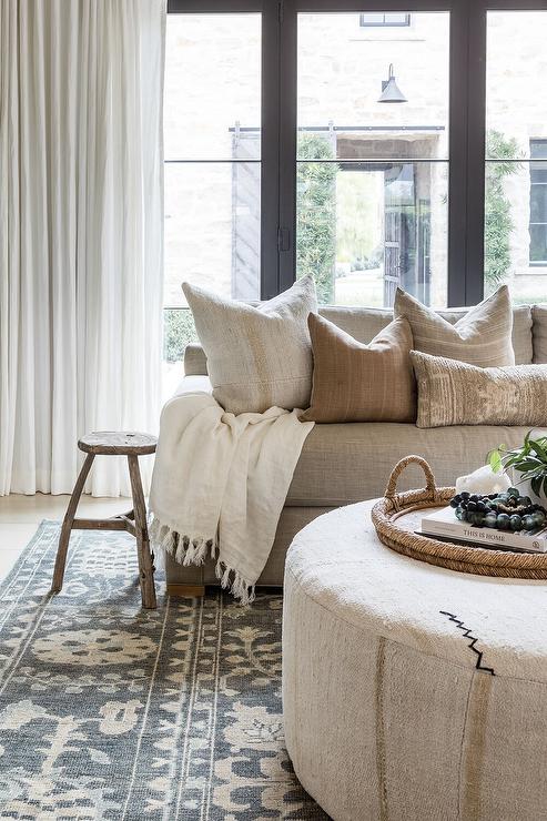 neutral living room featuring a neutral ottoman styled with woven tray