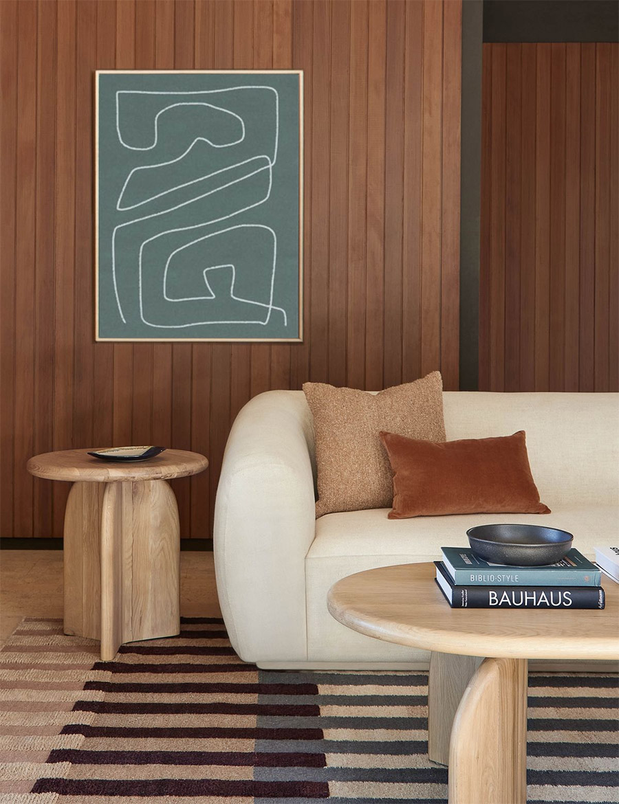 living room with brown wood paneling, neutral beige sofa and a striped rug