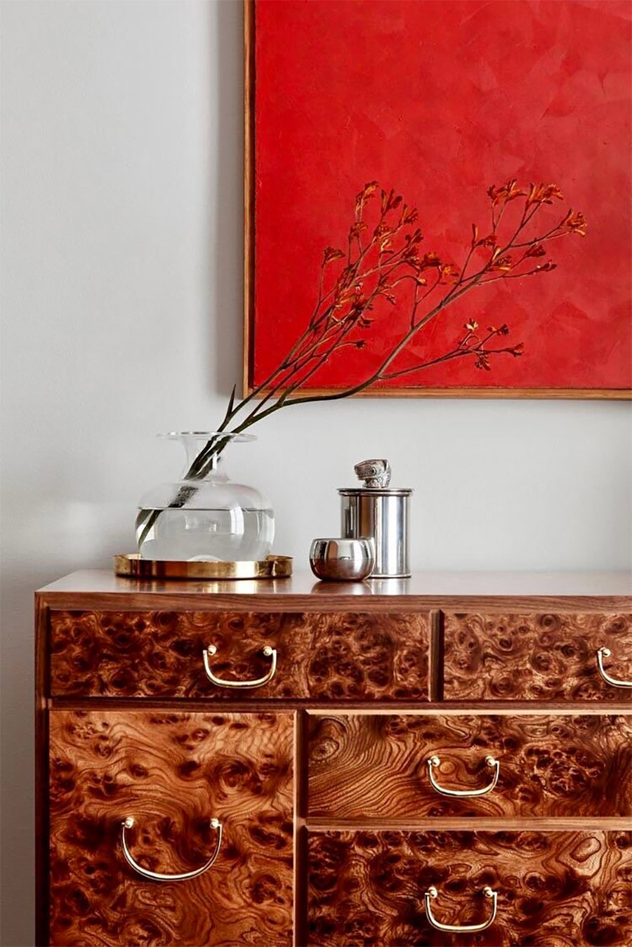 brown burlwood dresser paired with striking red artwork