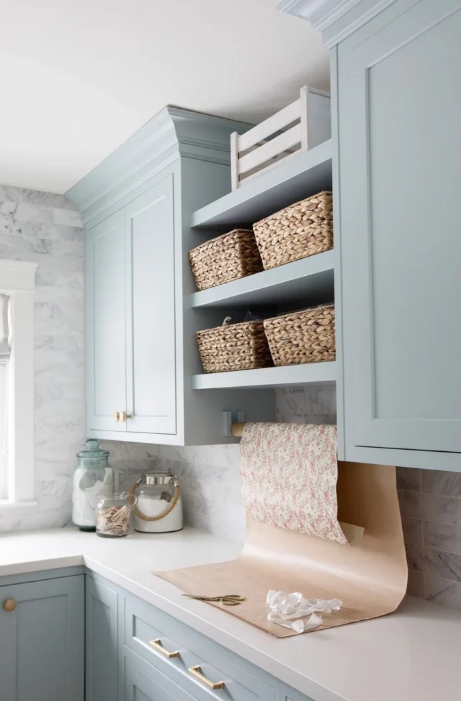 A pale blue laundry room with marble tiles and light bright counters