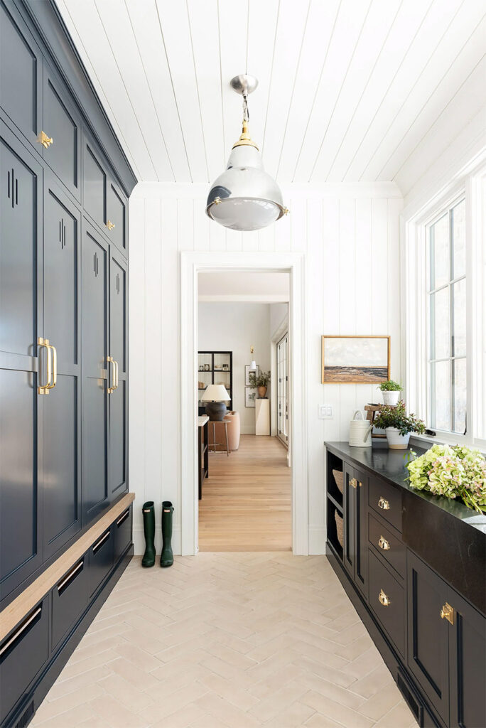benjamin moore swiss coffee painted walls with navy blue storage cabinets, gold hardware, and herring bone floors