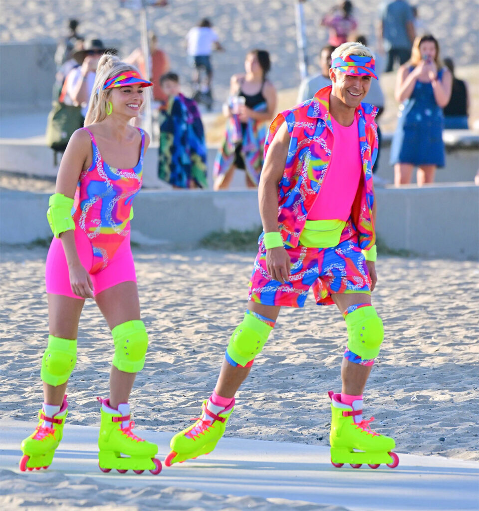 Margot Robbie and Ryan Gosling wearing neon attire while rollerblading on the Barbie movie set